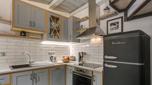 A modern kitchen with grey cabinets, a black refrigerator, and a built-in oven.