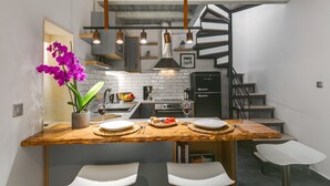 A modern kitchen with a wooden island, white bar stools, and a staircase leading to an upper level.