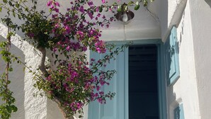 A white building with a blue door and a hanging light fixture.