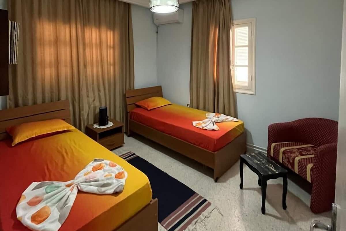 Ein Hotelzimmer mit zwei Betten, einem Schreibtisch, einem Stuhl und einer Pendelleuchte.