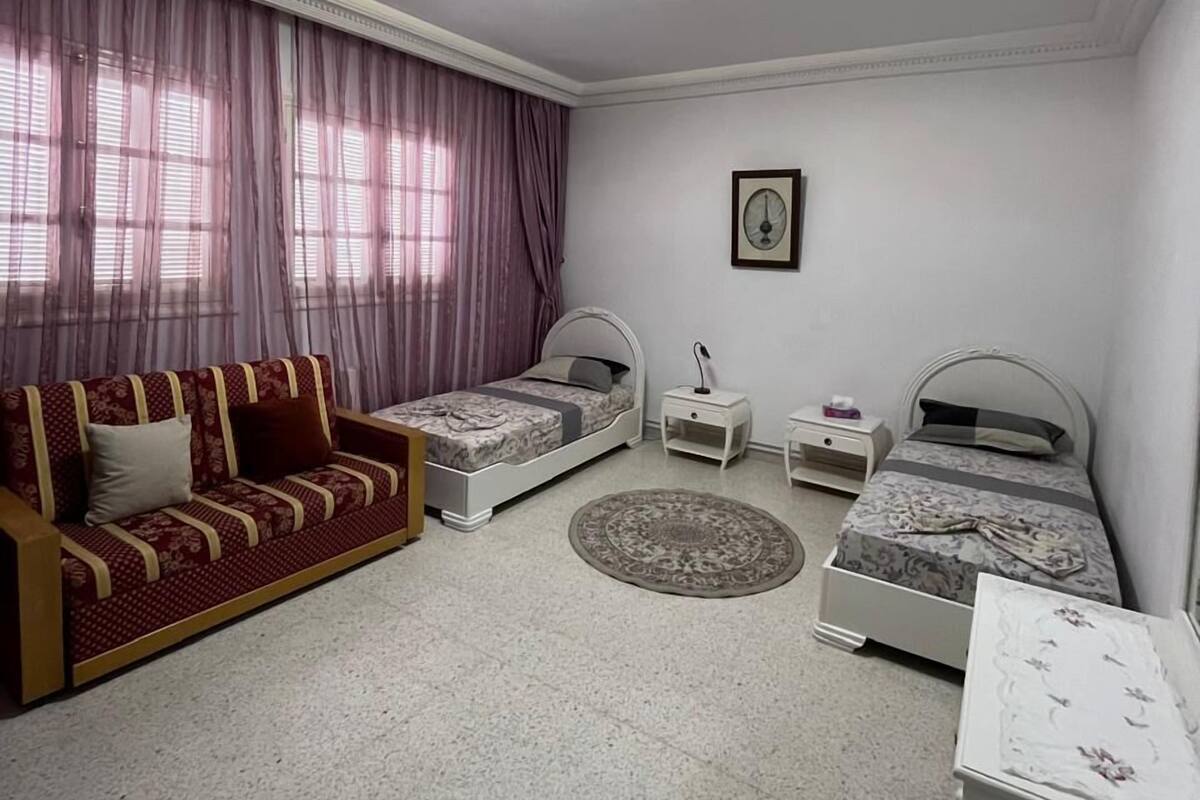 Ein Schlafzimmer mit zwei Einzelbetten, einem Schlafsofa, einem kleinen Tisch und einem Nachttisch.