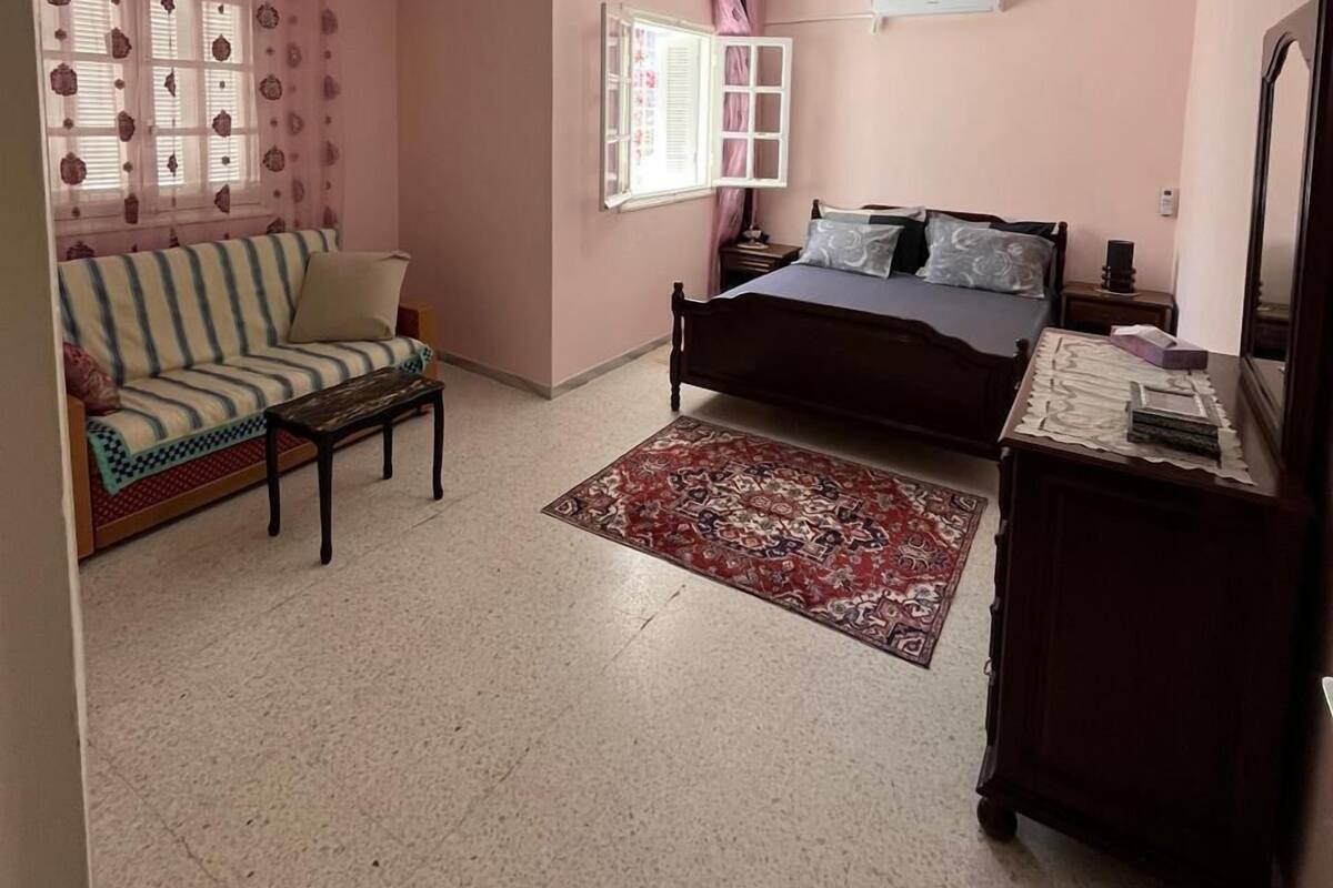 Ein Schlafzimmer mit Bett, Sofa, einem kleinen Tisch, Teppich und einem Schminktisch.