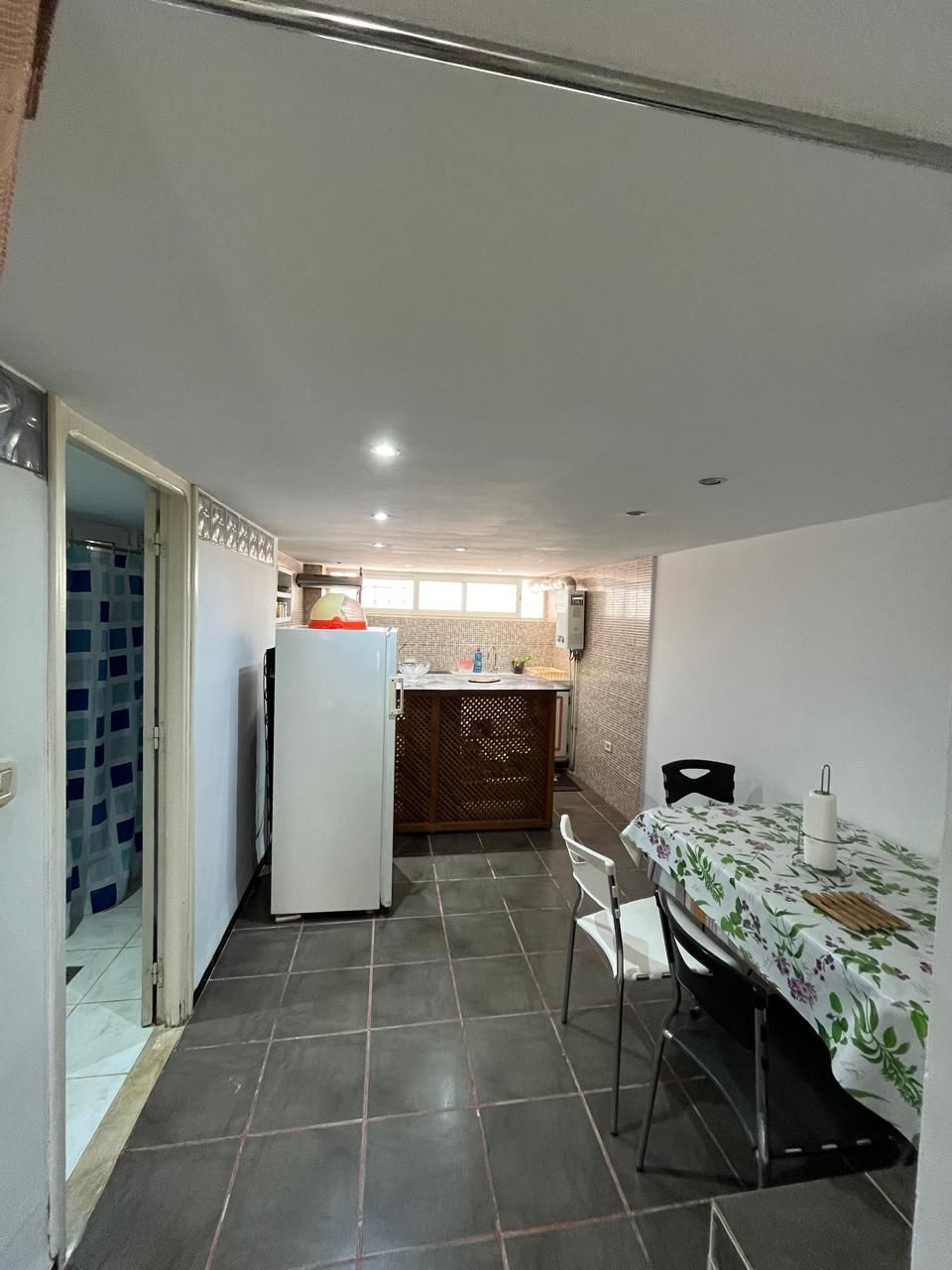A compact kitchen with a refrigerator, a dining table with chairs, and a small island with a sink.
