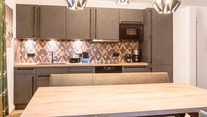 A modern kitchen with a central island, built-in appliances, and pendant lighting. - Holiday Apartment near ski slope (Turracher Höhe)