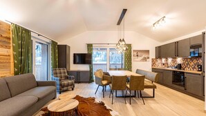 A modern living room with a sofa, dining table, chairs, and a TV. - Holiday Apartment near ski slope (Turracher Höhe)