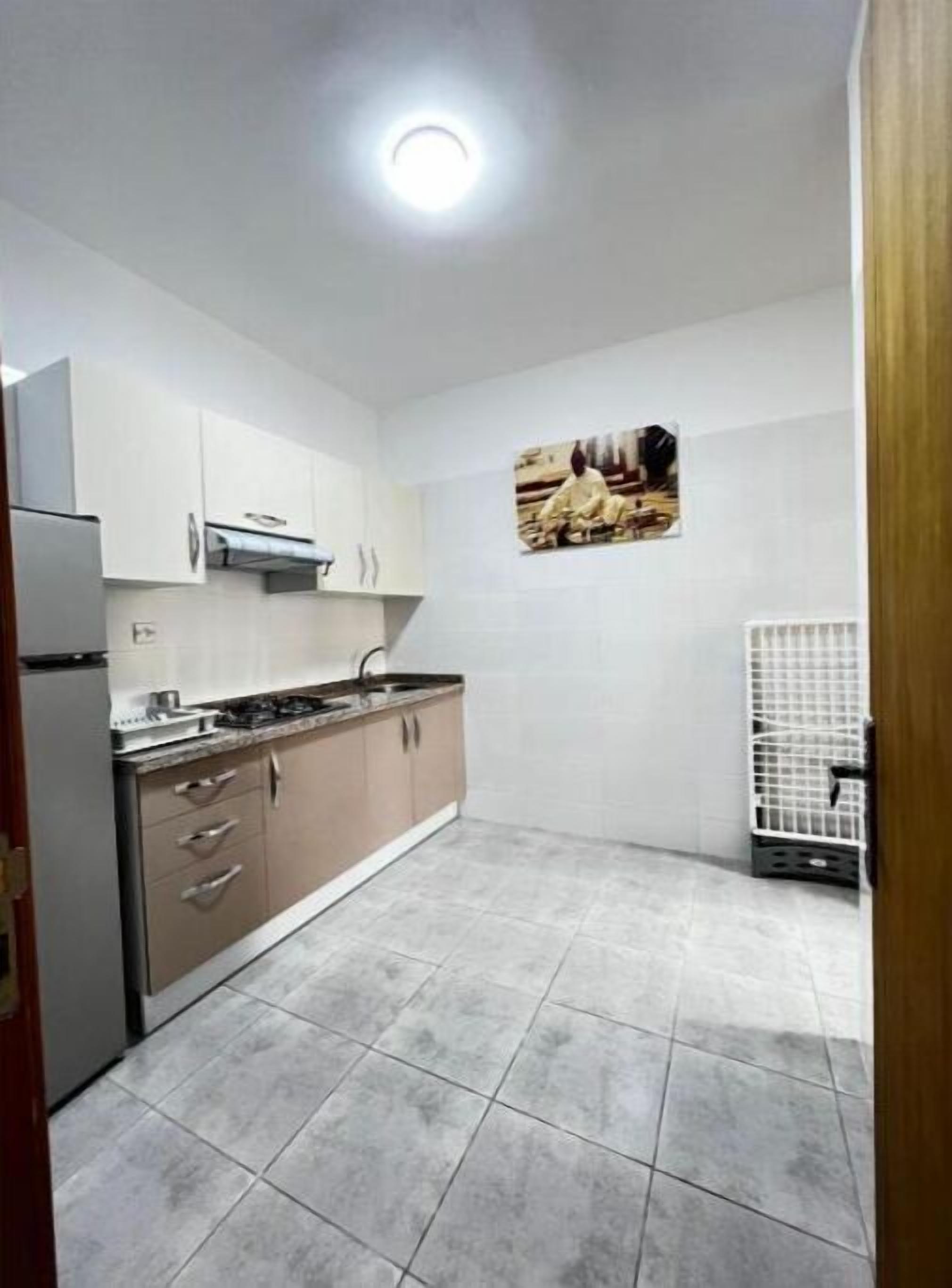 A kitchen with white cabinets, a stove, and a tiled floor.