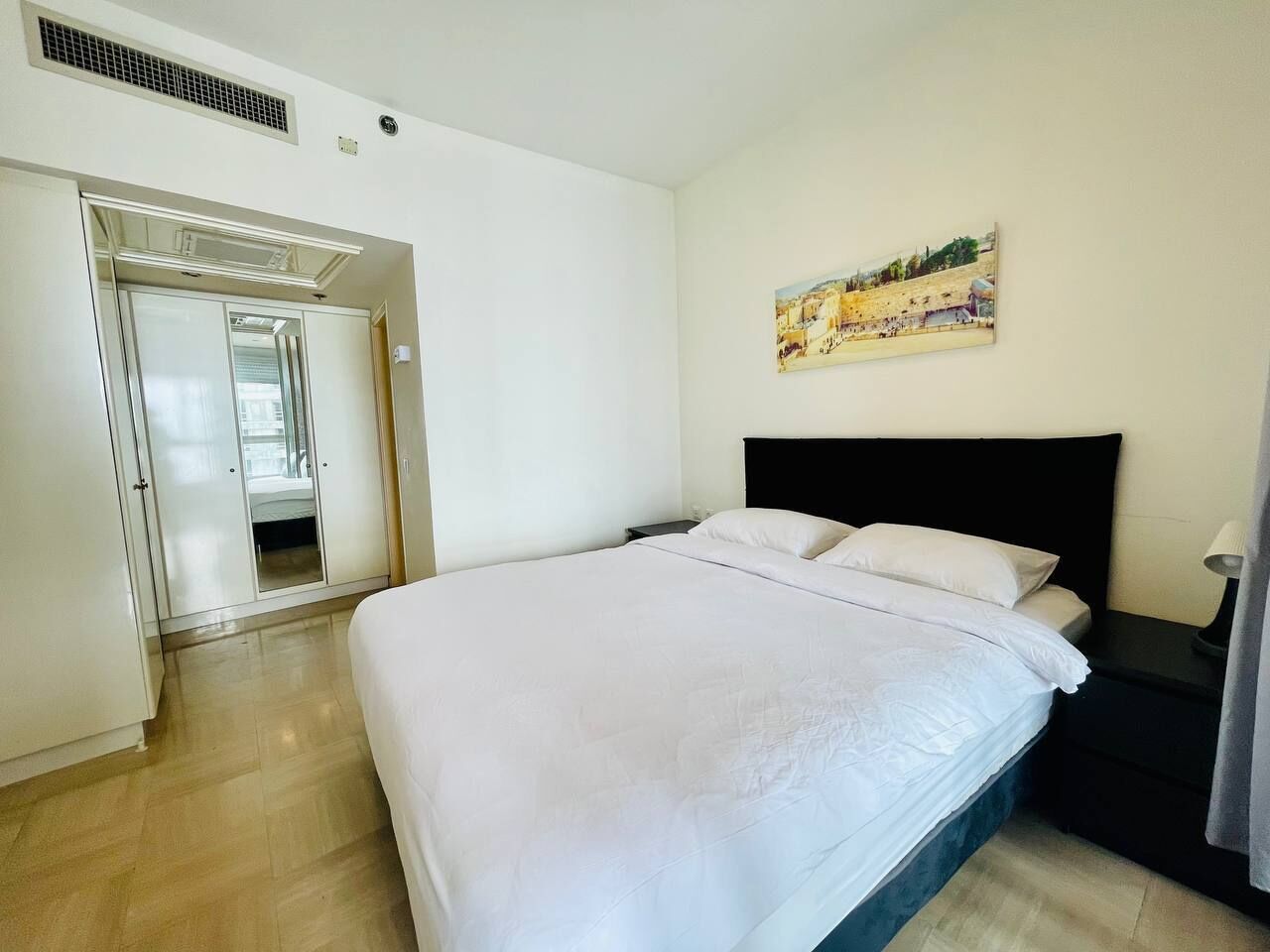 Un dormitorio con una cama grande, un armario y un cuadro en la pared.