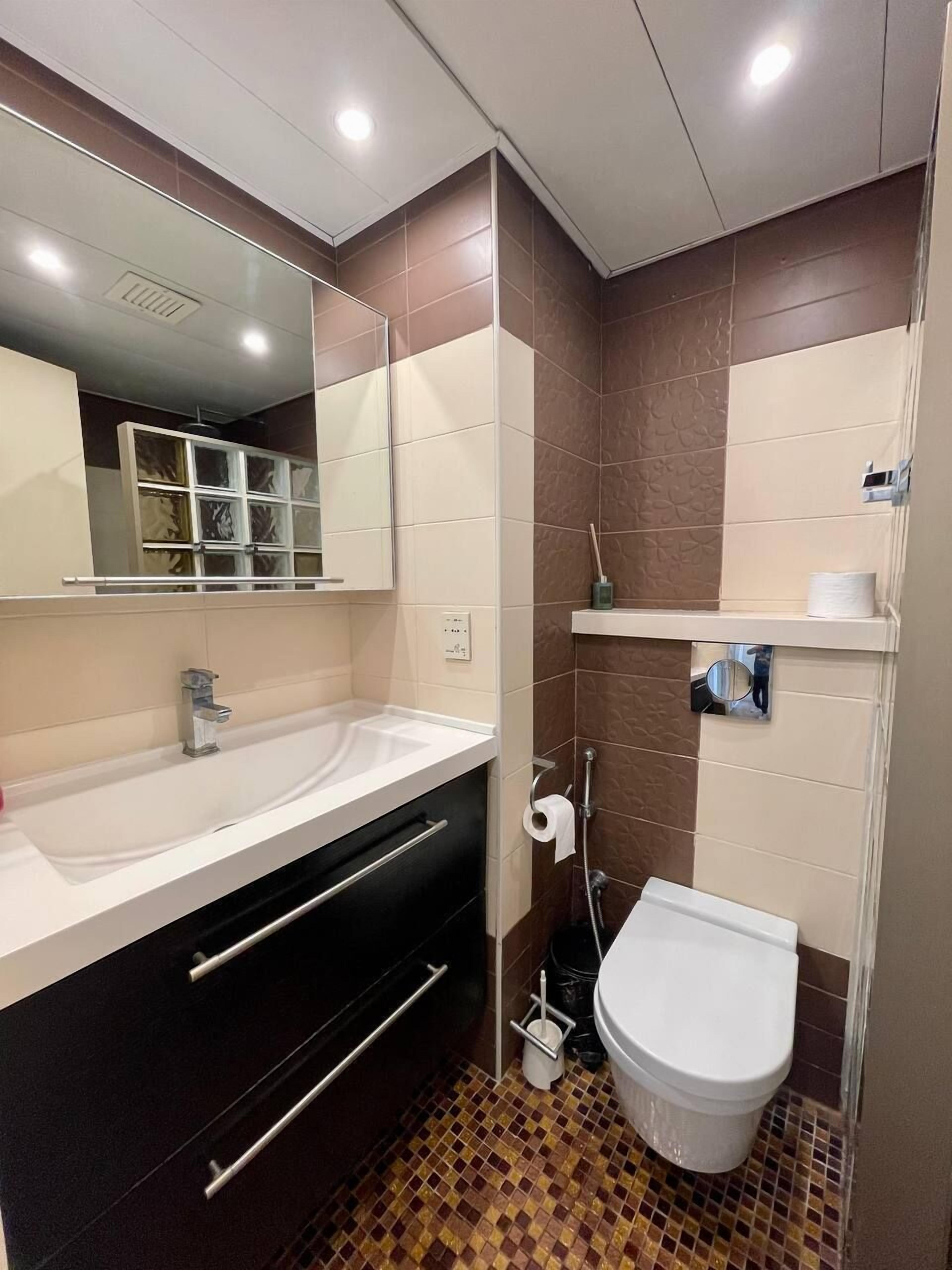 Um banheiro moderno com pia branca, armário preto e vaso sanitário.