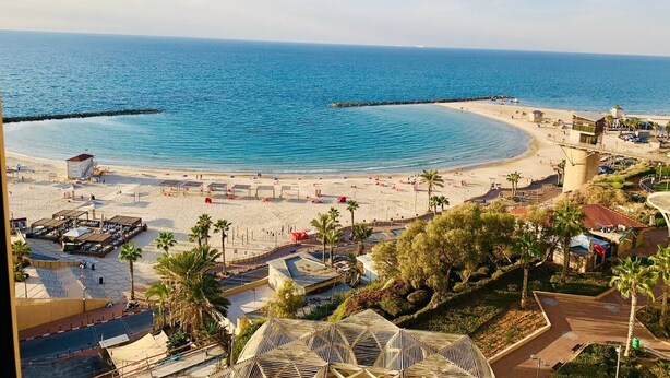 Un complexe hôtelier de bord de mer offrant une vue dégagée sur l’océan, une plage de sable et une jetée s’avançant dans l’eau.