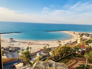A beach resort with a clear view of the ocean, a sandy beach, and a pier extending into the water. - Royal on the Sea (Netanya)