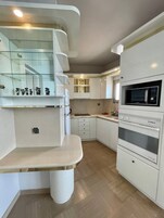 Una cocina funcional con armarios blancos, microondas y horno integrado.