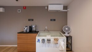 A hotel room with a wooden cabinet, a coffee machine, a glass display case, a fan, and an air conditioning unit. - HOTEL R9 The Yard Tsuchiura (Tsuchiura)