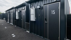 A row of industrial-style buildings with numbered doors, likely indicating hotel rooms or units. - HOTEL R9 The Yard Tsuchiura (Tsuchiura)