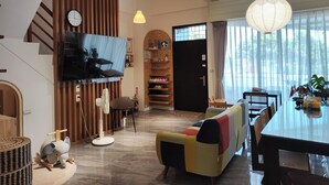A modern living room with a sofa, a dining table, a TV mounted on a wall, and a large window with curtains. - Nan Ping Ourhill B&B (Dongshan)