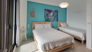 A bedroom with two beds, a teal accent wall, a colorful painting, and a pendant light. - Nan Ping Ourhill B&B (Dongshan)