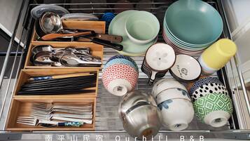 A kitchen drawer with various utensils, plates, and bowls.