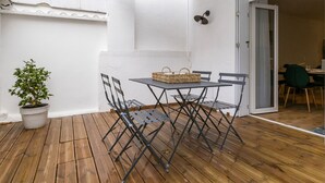 A patio with a table and chairs, a potted plant, and a striped awning.