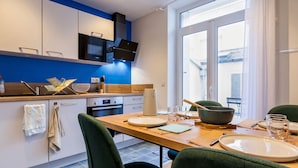 A modern kitchen with a dining area, featuring a large window, a built-in oven, and a flat-screen TV.