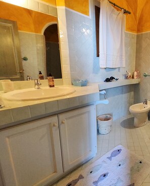 Ein Badezimmer mit zwei Waschbecken, einer Toilette, einem Spiegel und einem Handtuchhalter.