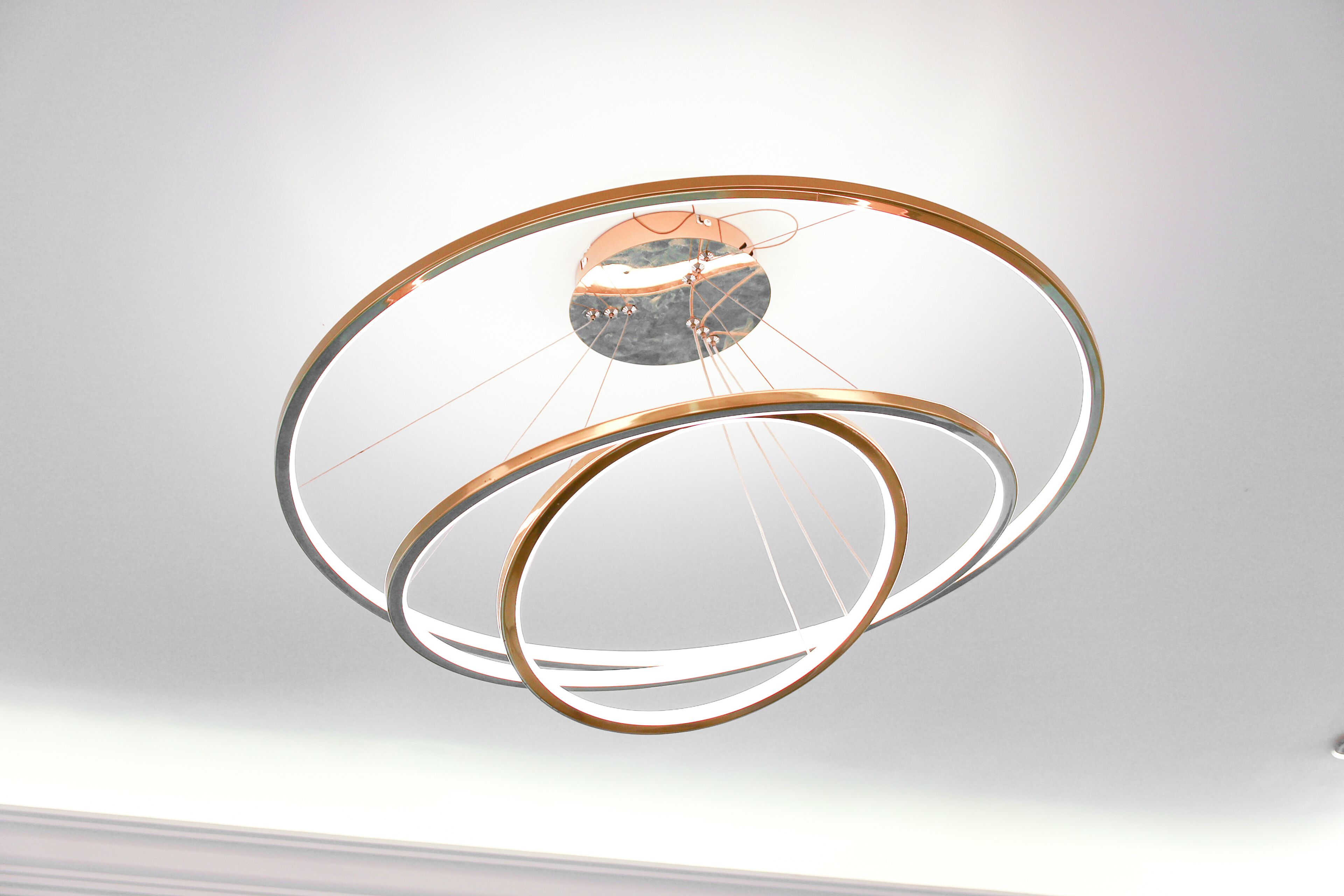 A modern, circular chandelier with multiple rings and a central reflective element.