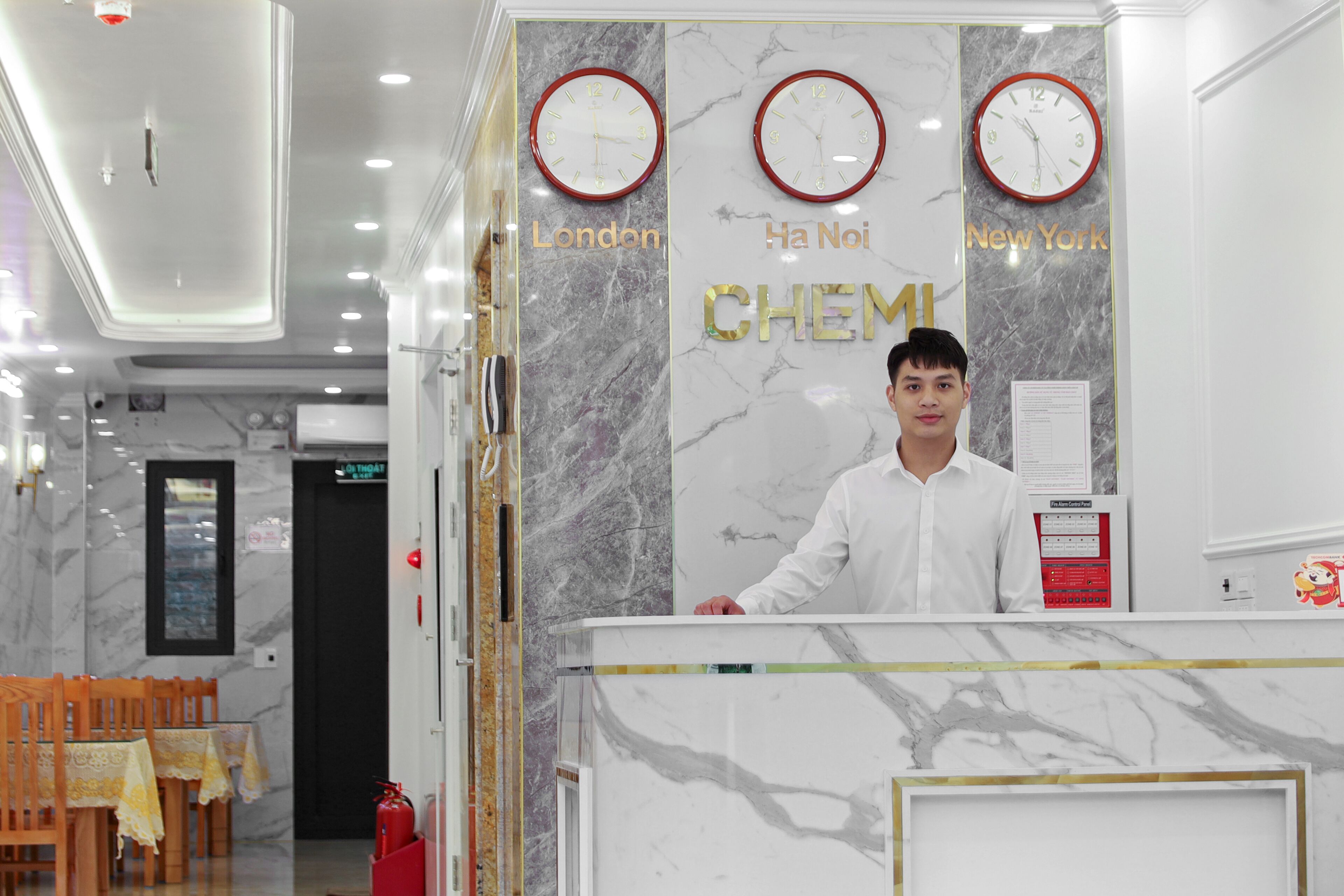 Een hotel receptiebalie met klokken die de tijd in Londen, Hanoi en New York weergeven.
