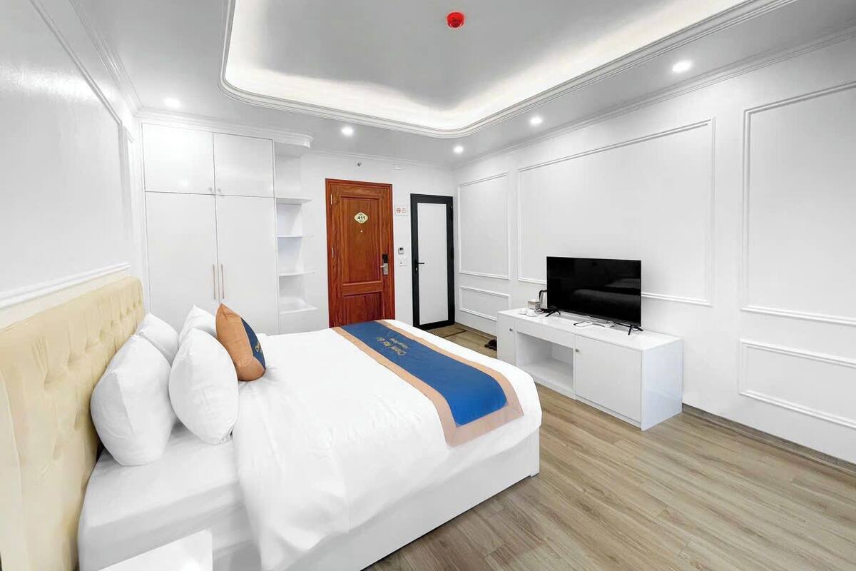 Una habitación de hotel moderna con una cama grande, un televisor y un escritorio.