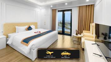 A hotel room with a bed, a chair, a TV, and a small table. There is a sign indicating a taxi service available 24/7 and a shuttle from the airport in 5 minutes.