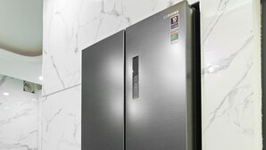 Una cocina moderna con un refrigerador de acero inoxidable de doble puerta frente a una pared de mármol.