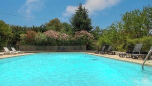Una piscina con sillas de descanso y una cerca de madera.