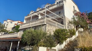 A multi-story building with balconies, a stone facade, and a staircase leading up to the entrance. - Apartments Sponga (Mljet)