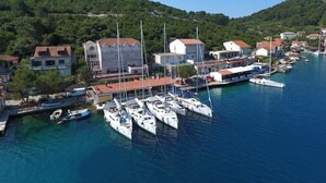 A marina with multiple yachts docked, surrounded by buildings and a hilly backdrop. - Apartments Sponga (Mljet)