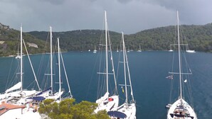 A marina with multiple sailboats docked, surrounded by a hilly landscape. - Apartments Sponga (Mljet)