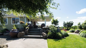 A house with a covered porch, a stone staircase, and a well-maintained garden with rocks and plants.