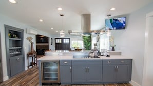 A modern kitchen with grey cabinets, a central island, and a built-in dishwasher.