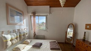 A bedroom with a bed, a dresser, a mirror, a window with curtains, and a framed picture on the wall.