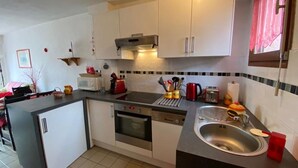 A compact kitchen with white cabinets, a microwave, a toaster, and a sink.