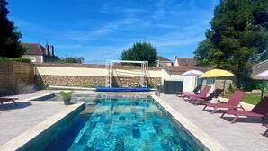 A rectangular swimming pool with clear blue water, surrounded by stone walls and a paved deck. - Maison Bourgogne 400m2, 2 Piscines Intérieure/extérieure,spa, Commerces à 50m (Gueugnon)