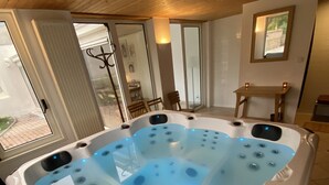 A spa-like room with a large, white, freestanding hot tub featuring multiple jets and LED lighting. - Maison Bourgogne 400m2, 2 Piscines Intérieure/extérieure,spa, Commerces à 50m (Gueugnon)