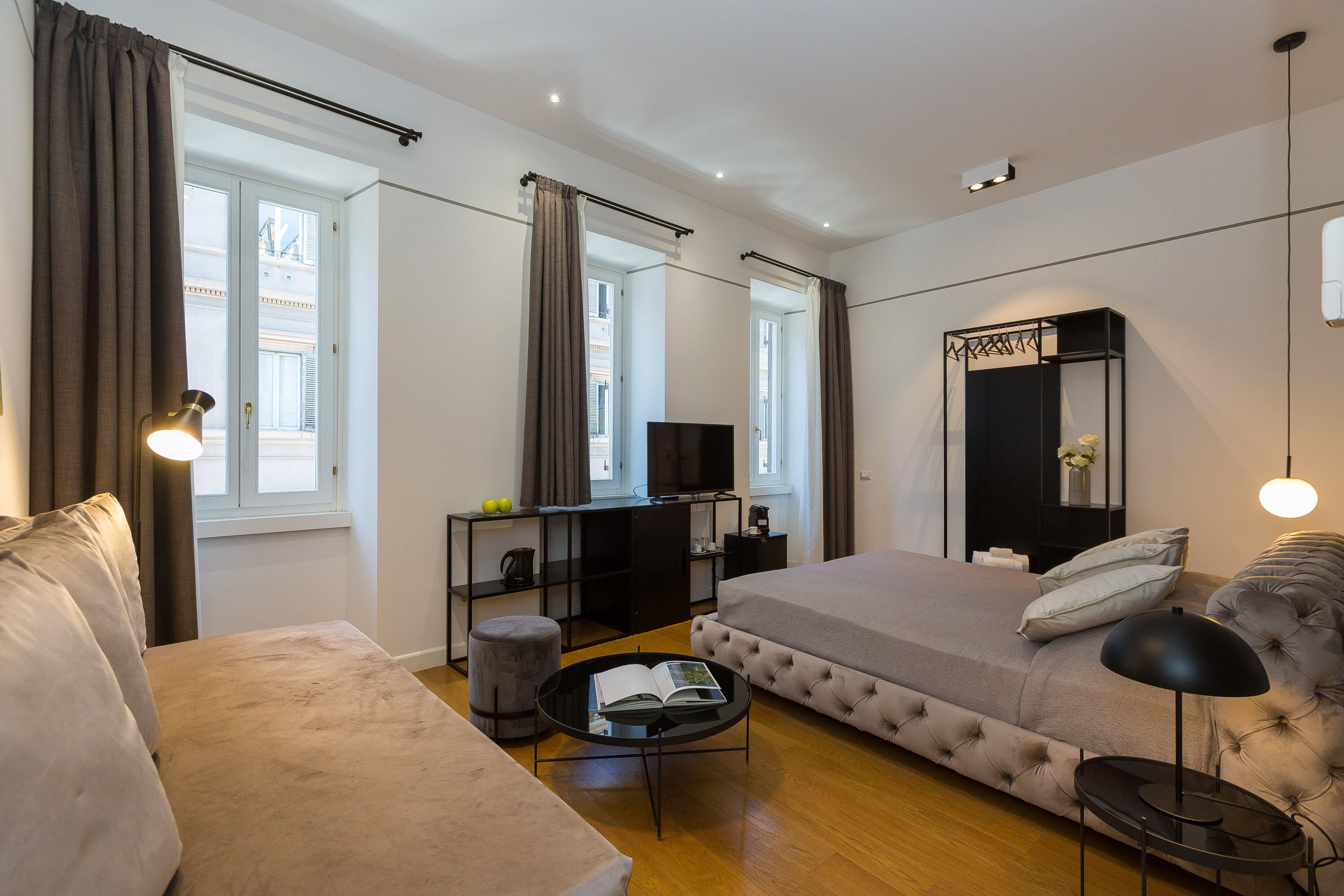 A modern bedroom with a bed, a sofa, a TV, and a mirror.