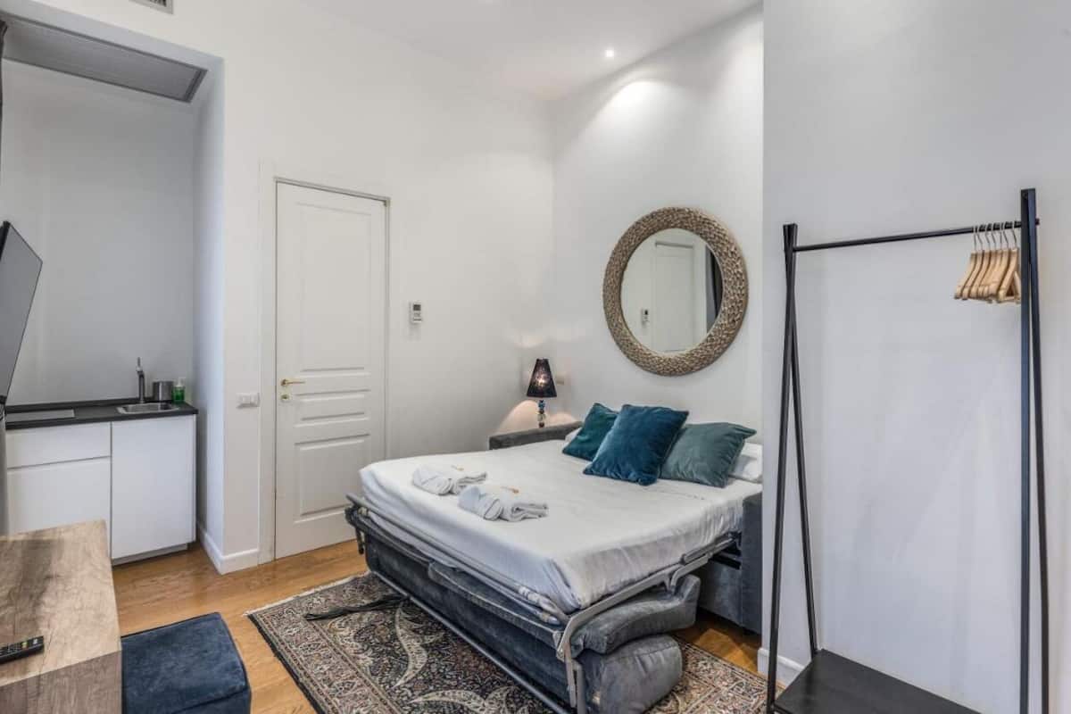 A bedroom with a bed, bedside table, lamp, and a wardrobe.