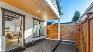 Ein modernes Haus mit überdachter Terrasse, Holzzaun und blauem Himmel.