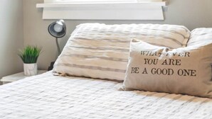 A bedroom with a bed, pillows, a bedside lamp, and a small potted plant. - Walk to the waterfront! The Cozy Cottag (Tacoma)