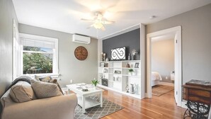 A living room with a sofa, coffee table, and a bookshelf. - Walk to the waterfront! The Cozy Cottag (Tacoma)