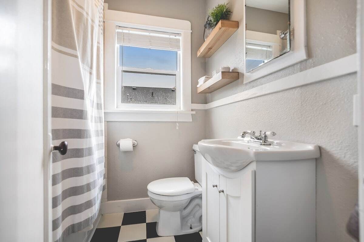 Ein kleines Badezimmer mit Toilette, Waschbecken und einem Fenster mit Ausblick.
