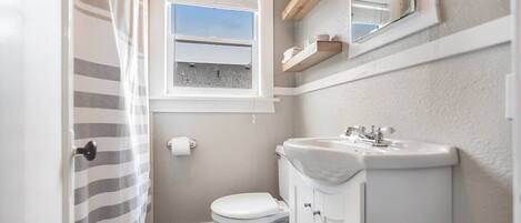 Ein kleines Badezimmer mit Toilette, Waschbecken und einem Fenster mit Ausblick.