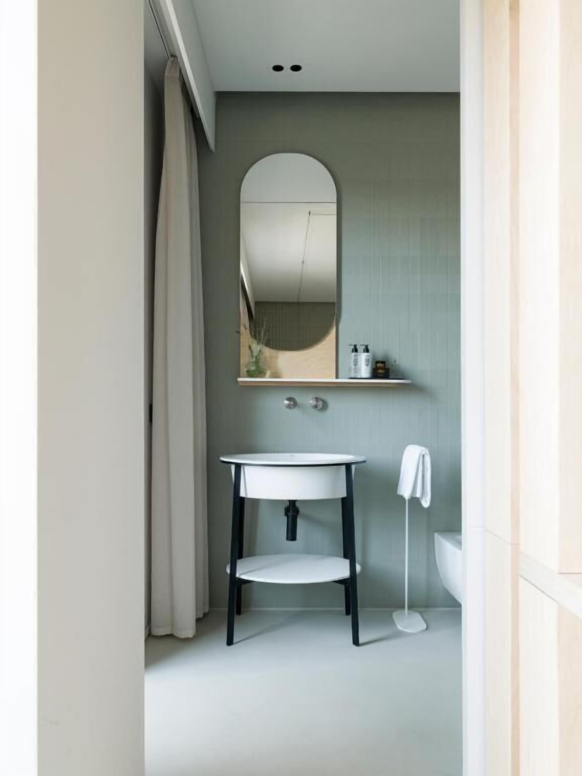 Un baño moderno con lavamanos blanco, un espejo y un inodoro.