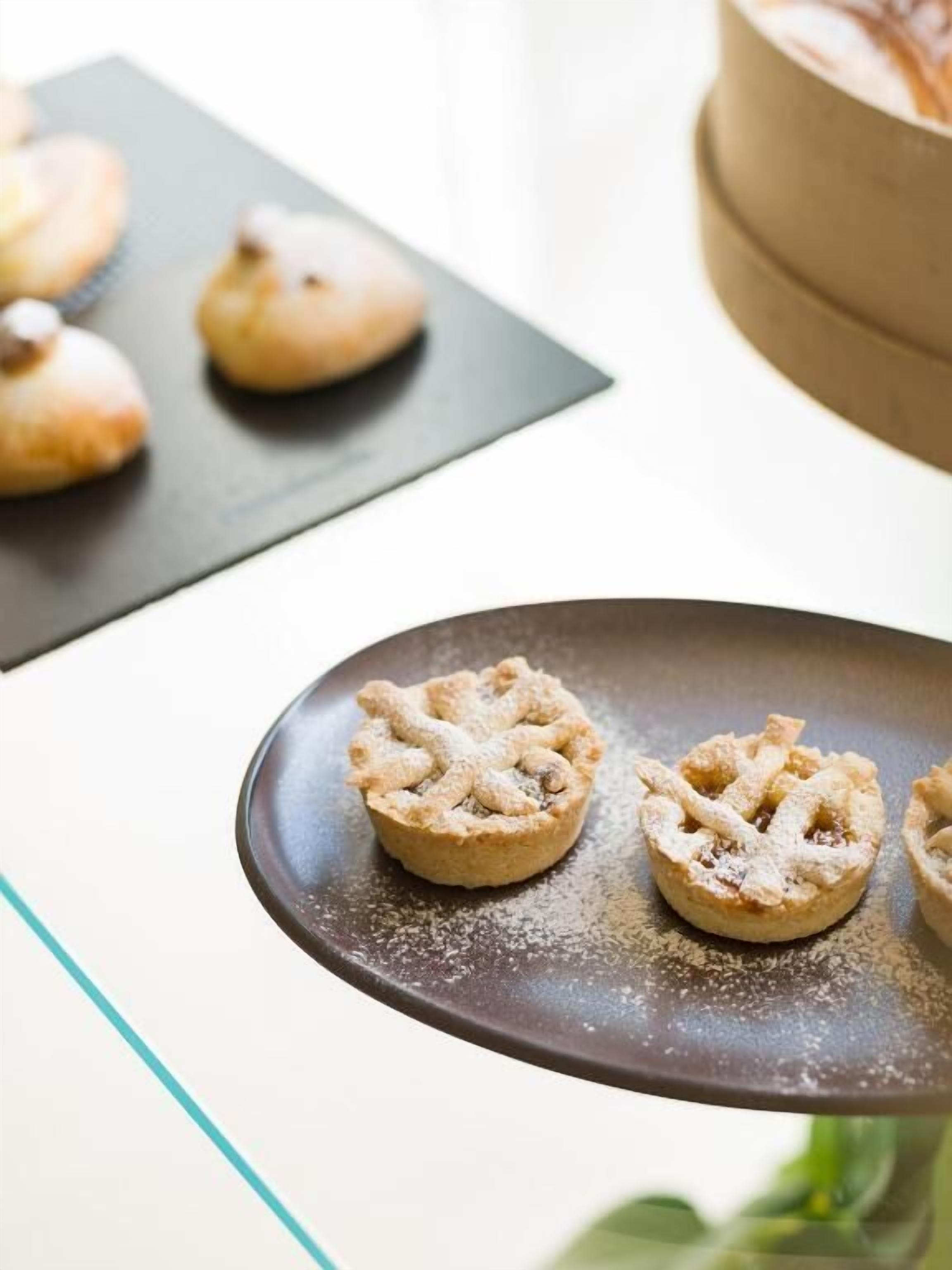 A dessert plate with two tart pastries on a dark plate, set on a table with a blurred background.