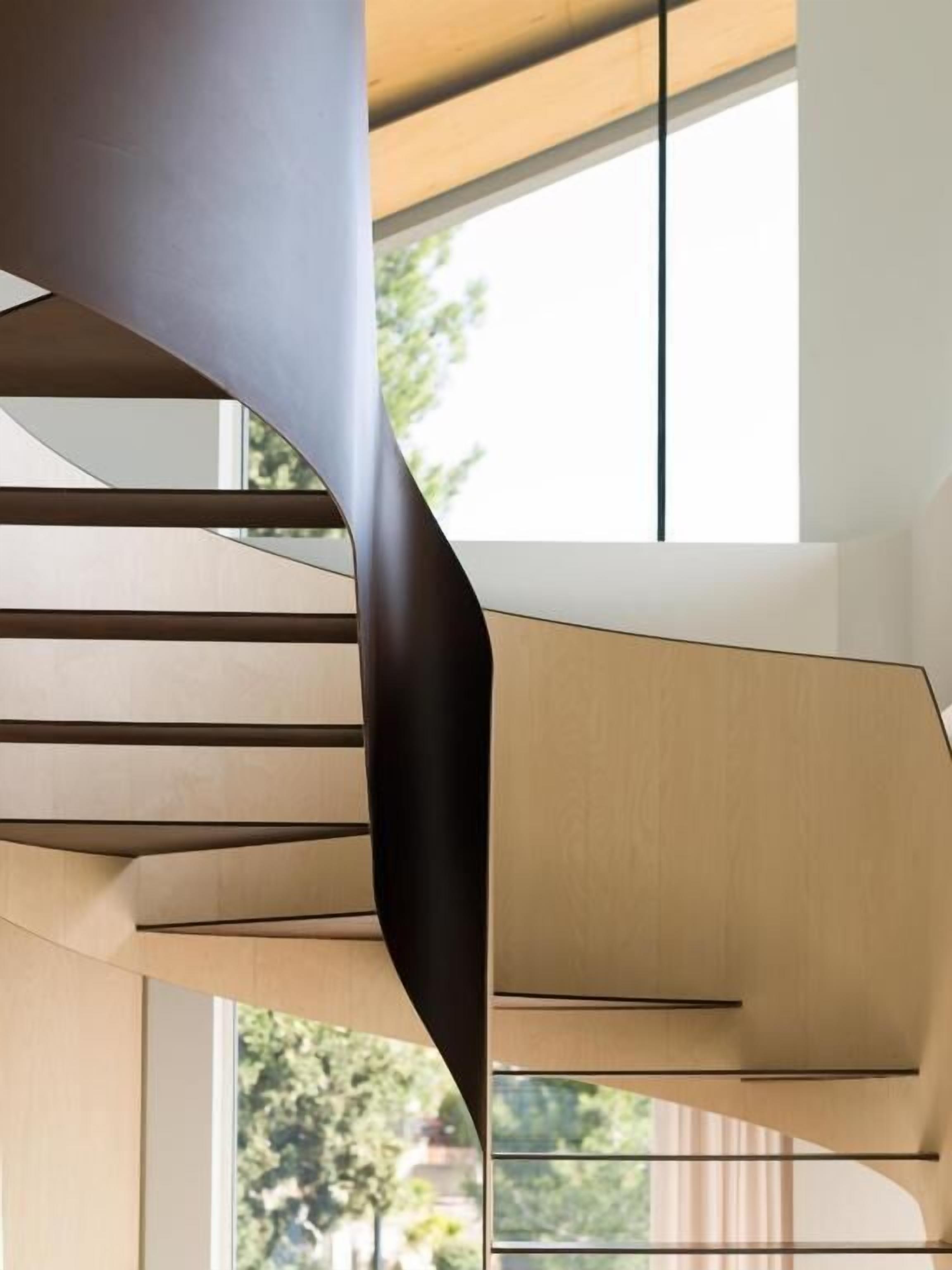 A modern interior with a curved staircase and large windows.