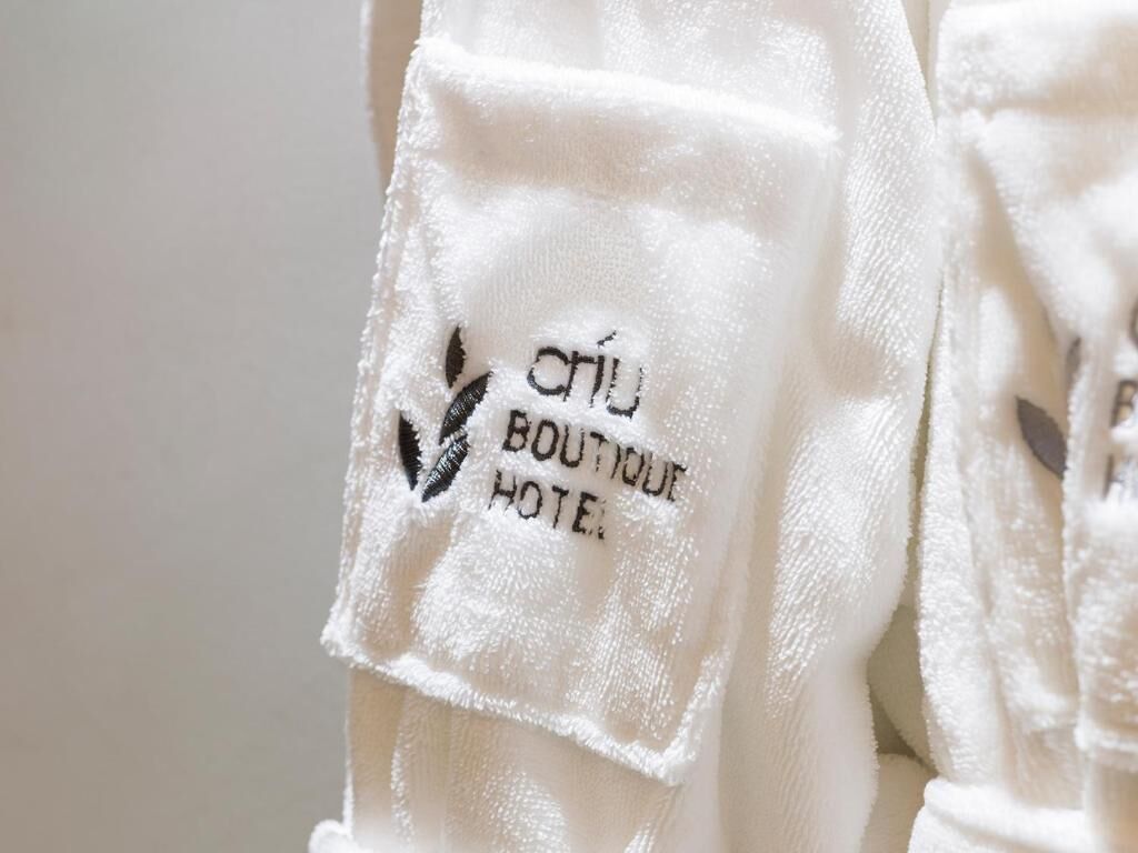 A white towel with embroidered text reading "CHU BOUTIQUE HOTEL".