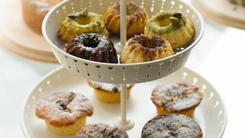 A tiered serving tray with various pastries, a glass dome cover, and a plate with additional pastries.